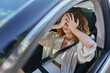 © SHOTPRIME STUDIO - frustrated woman in car covering face with hands, wearing beige jacket and white top, sitting in driver seat with seatbelt fastened during daytime.