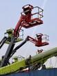© vipvn - Eyecatching and colorful lifting equipment can be seen at this busy construction site. A vibrant collection of industrial lift equipment stands against a clear sky at a construction site