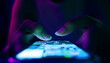 © Urupong - Finger of woman touching scroll page app on mobile phone.In a room with blue and purple neon tones.concept Social media and marketing