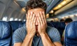 © NusratJahan - Distressed man covering face while flying on airplane, fear of flying travel photo concept
