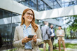 © Miljan Živković - Smart businesswoman use cellphone in front of modern office building
