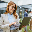 © Miljan Živković - Smart businesswoman use laptop in front of modern office building