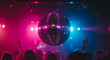 © SULTAN - A shiny disco ball hanging above a crowd of people in a nightclub with colorful lighting effects
