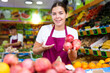 © JackF - Young saleswoman proposing pomegranate, offering fresh fruits in supermarket