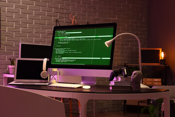 Wall Mural - programmer's workplace with computer, laptop and glowing lamp in dark office