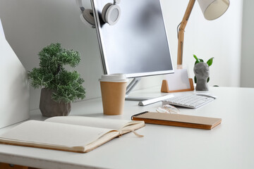 Notebooks, modern computer and cup of coffee on light table, closeup