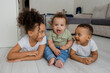 © Tina kids photo - three African-American children lie on the wooden floor of a house