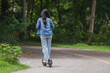© crizzystudio - Woman riding electric scooter in lush green park