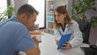 © Krakenimages.com - Doctor woman using tablet with patient man in hospital room discussing medical care details and healthcare solutions, emphasizing professional setting indoors.