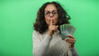 © Krakenimages.com - Middle-aged woman holding russian ruble banknotes signals silence against a vibrant green background, creating a mysterious financial scene.