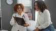 © Krakenimages.com - Doctor discussing medical results with patient in clinic, highlighting healthcare setting with two mature hispanic women consulting in an indoor hospital room.
