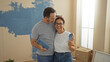 © Krakenimages.com - Hispanic couple painting new home together in living room, showcasing love and teamwork as middle-aged man and woman renovate their cozy indoor space.