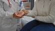 © Krakenimages.com - Doctor checking pulse of woman patient in clinic room showcasing medical care indoors with nurse observing health examination professionally.