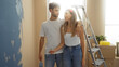 © Krakenimages.com - Man and woman painting new home together in living room, sharing moment as couple near ladder with boxes, expressing love and teamwork for interior renovation.