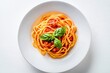 © Fazila - Spaghetti pasta. full plated serving of bigoli with tomato sauce basil pasta. Minimalist white ceramic plate.