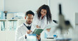 © peopleimages.com - Science, talking and people on tablet in lab with microscope for analysis, medical research and study. Biology, pharmaceutical team and man with woman on tech for results, review and online report