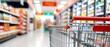 © Mujeeb - Blurred shelves in grocery store and trolley.Copy space for text or design.shopping cart handle with yellow grip red accents, Shopping cart in supermarket.Part of shopping trolley in supermarket aisle