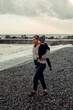 © Doralin - Mother holding child while walking on pebble beach by the sea