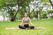 © wichayada - Yoga practice in nature. Young woman meditating peacefully on a yoga mat outdoors.