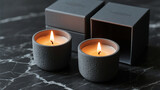 Two lit grey candles on dark marble surface with boxes