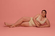 © Lustre Art Group  - A Caucasian woman embraces body diversity while wearing comfortable underwear against a pink background. Concept of self-love and body positivity in fashion.
