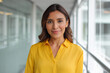 © EricMiguel - Confident Young Woman in Bright Yellow Shirt Smiling in Modern Office Corridor