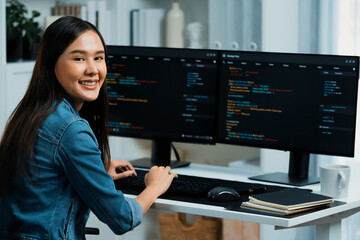young asian in it developer looking at camera to present with online information on pc with coding p