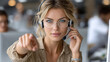© scaliger - Confident call center agent with headset in busy office environment, young woman pointed