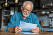 © mattegg - Senior man reading letter in kitchen