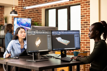 black female engineer seated at shared workstation, developing industrial machinery models with adva