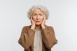 © LimeSky - An anxious elderly woman distressed by bad news reacts nervously shaking her hands and expressing concern while staring indecisively at the camera against a white background