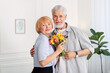© New Africa - Lovely senior couple with bouquet of flowers at home