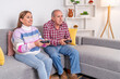 © Guillermo Spelucin - Happy senior couple playing videogames on the couch at home