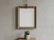 © Mobasshara - Wooden picture frame hangs on a wall above a small potted plant