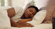 © peopleimages.com - Tired, dream and black woman with sleeping in bed for resting, peaceful and comfortable on pillow. Exhausted, person and asleep in home for lazy weekend, relax and recovery from fatigue in bedroom