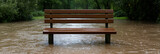 Park bench submerged in floodwaters. A reminder of nature's power and changing landscapes. Flooded area, wooden bench, nature’s force.