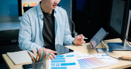 Asian male programmer working with tablet, laptop, and desktop in tech office. Coding, software development