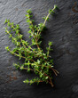 © NanoStudio - Fresh thyme branches arranged on dark slate background, showcasing vibrant green leaves