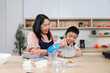 © wichayada - Family Cooking Together. A cheerful mother assists her son while they mix ingredients in the kitchen.