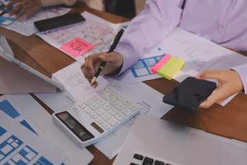 Close up ux developer and ui designer brainstorming about mobile app interface wireframe design on table with customer breif and color code at modern office.Creative digital development agency.