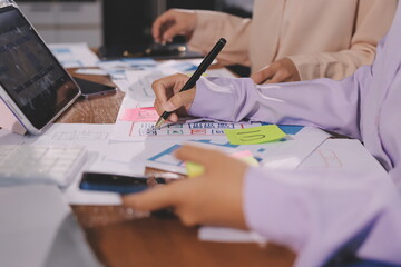 Close up ux developer and ui designer brainstorming about mobile app interface wireframe design on table with customer breif and color code at modern office.Creative digital development agency.