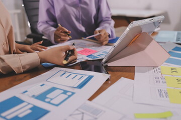 Close up ux developer and ui designer brainstorming about mobile app interface wireframe design on table with customer breif and color code at modern office.Creative digital development agency.