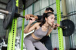 © itchaznong - Partner Workout. Woman squatting with support from trainer in gym.