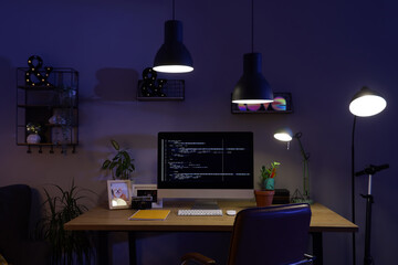 Wall Mural - interior of dark programmer's office with workplace and glowing lamps at night