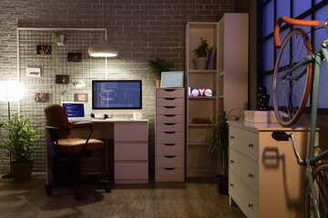 Wall Mural - interior of dark programmer's office with workplace, pin board and glowing lamps at night