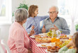 © Studio Romantic - Grandfather and little child boy talking while sitting at a dinner table full of homemade food together with grandma and other family members. Family, grandparents, young and old generation concept