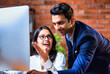 © StockImageFactory - Indian team using computer in modern office with exposed brick wall and teamwork focus