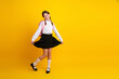 © deagreez - Adorable schoolgirl smiling in formal uniform against a bright yellow background, celebrating back-to-school season with joy