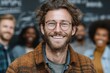 © River Girl - A cheerful man wearing glasses is smiling while standing in front of a diverse group of professionals who are brainstorming together.