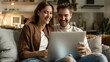 © Line - Couple smiling while looking at laptop on cozy sofa at home